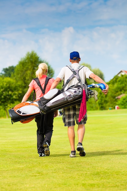 Jeune couple sportif jouant au golf sur un parcours