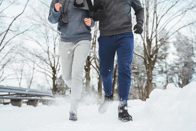 Jeune couple sportif pendant le jogging hivernal dans le parc enneigé de la ville