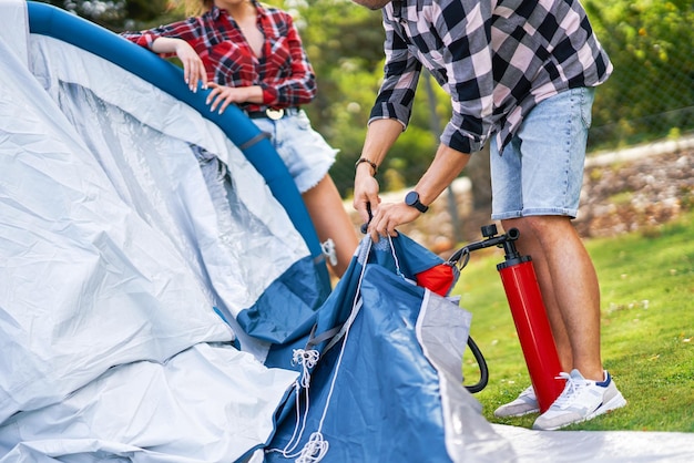 Jeune couple sympa s'amusant sur le camping en installant une tente. Photo de haute qualité