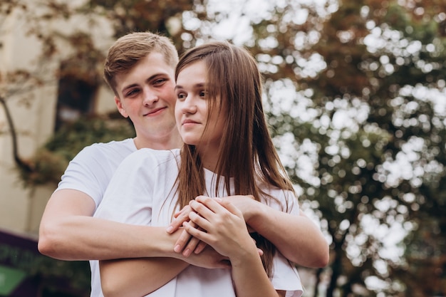 Jeune couple en t-shirts blancs et jeans se promène dans les rues de la ville et se tient la main.