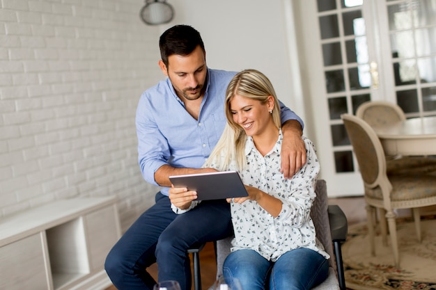 Jeune couple avec tablette dans la chambre