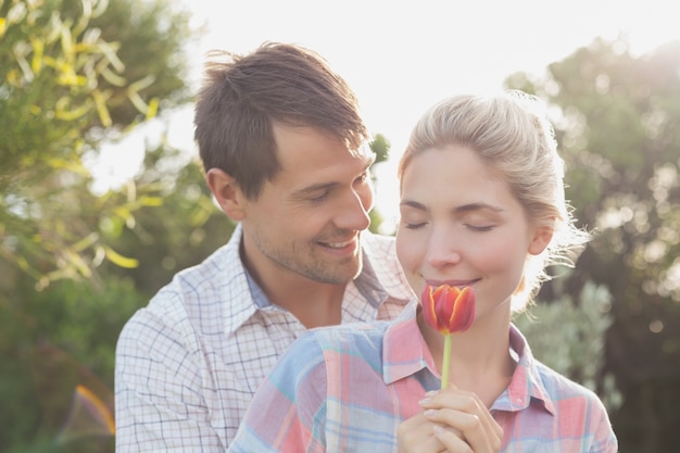 Jeune couple tenant une fleur dans le parc