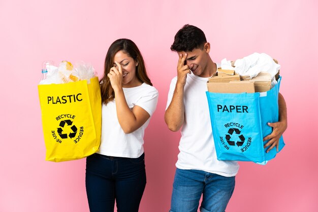 Jeune couple tenant un sac plein de plastique et de papier rose en riant