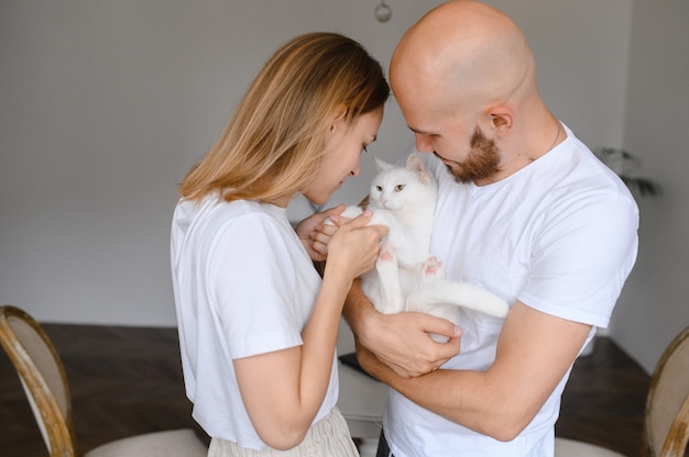 Jeune couple tient un chat blanc dans leurs bras