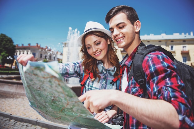 Jeune couple de touristes consultant la carte par une journée ensoleillée dans la ville