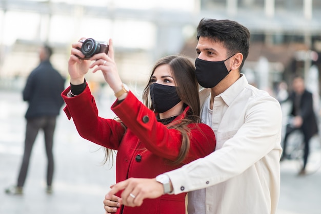 Jeune couple de touristes prenant des photos dans une ville pendant une pandémie de covid ou de coronavirus