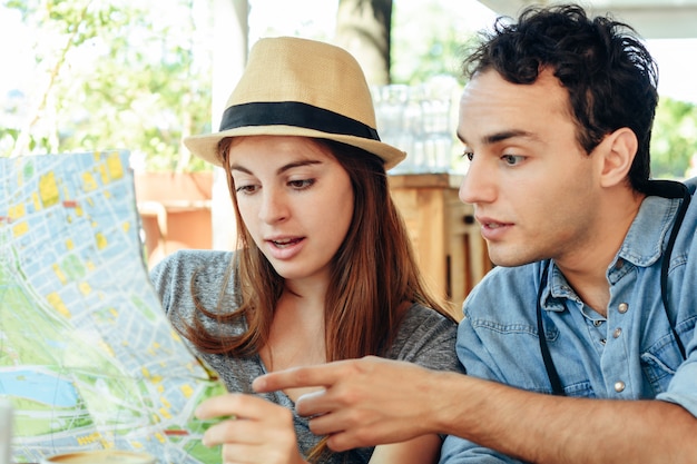 Jeune couple de touristes regarde une carte