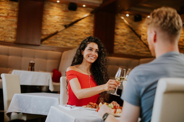 Jeune couple en train de déjeuner avec du vin blanc au restaurant