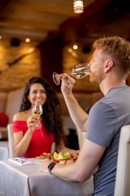 Jeune couple en train de déjeuner avec du vin blanc au restaurant