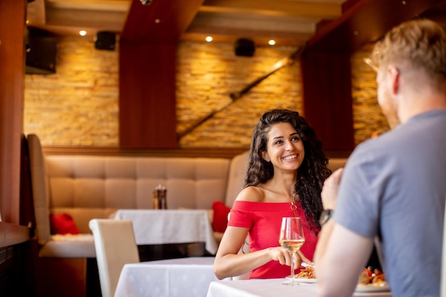 Jeune couple en train de déjeuner avec du vin blanc au restaurant