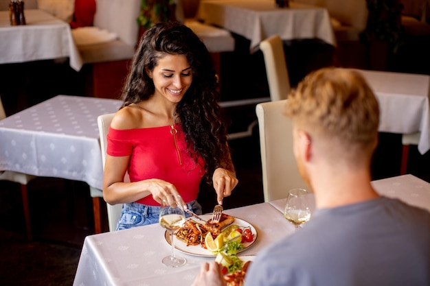 Jeune couple en train de déjeuner avec du vin blanc au restaurant