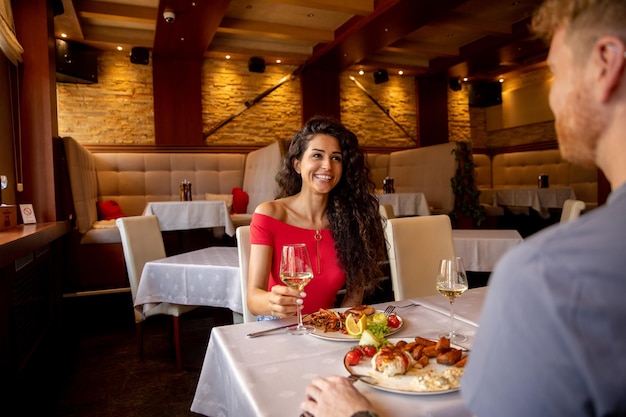 Jeune couple en train de déjeuner avec du vin blanc au restaurant