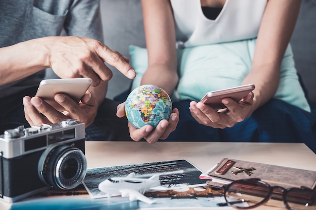 Jeune couple en train de planifier un voyage de vacances et de rechercher des informations ou de réserver un hôtel sur un téléphone intelligent