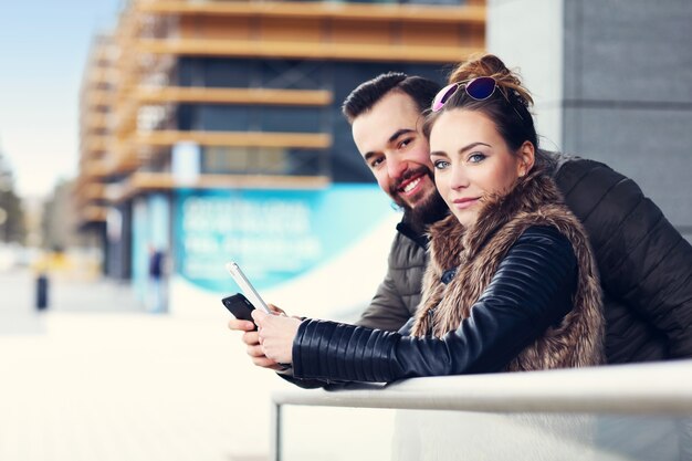 Photo jeune couple traîner en ville et envoyer des sms