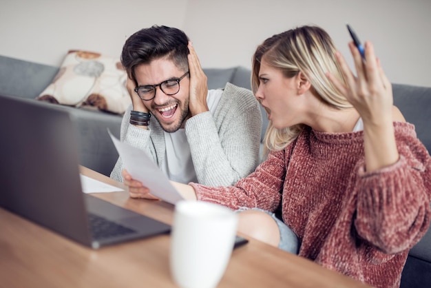 Jeune couple travaillant sur ordinateur portable à la maison