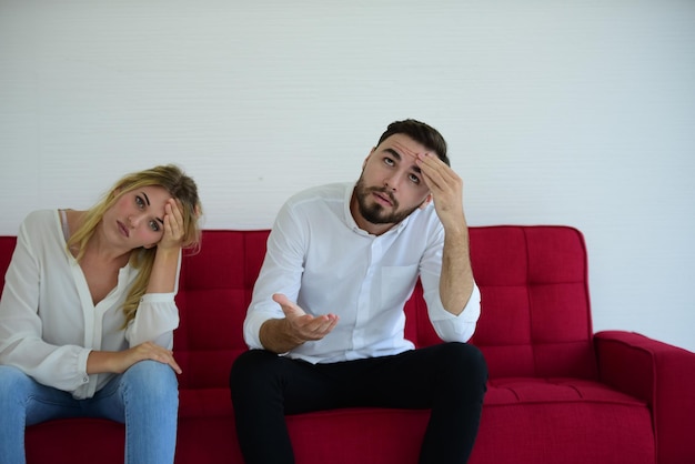 Un jeune couple triste assis sur le canapé à la maison.