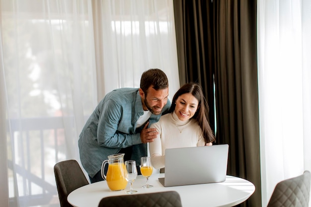 Jeune couple utilisant un ordinateur portable sur la table dans le salon