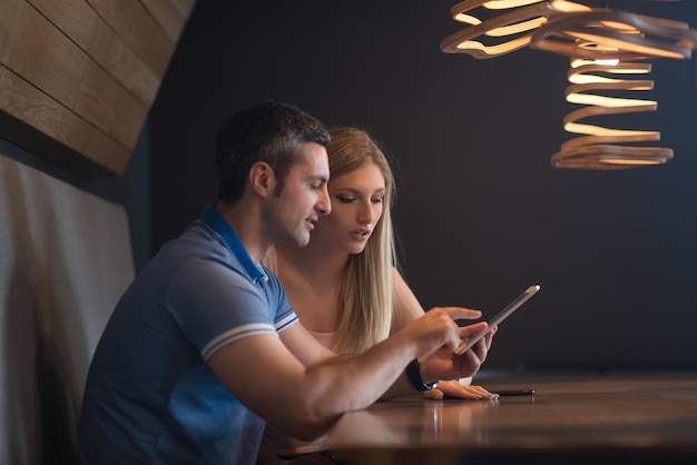 Jeune couple utilisant un ordinateur tablette à la maison de luxe ensemble, regardant l'écran, souriant.