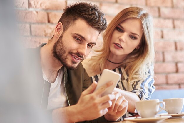 Jeune couple utilisant un smartphone dans un café-bar