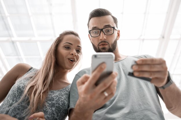 Jeune couple utilisant un smartphone pour faire des achats en ligne