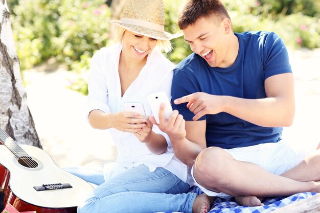 jeune couple utilisant des smartphones à la plage