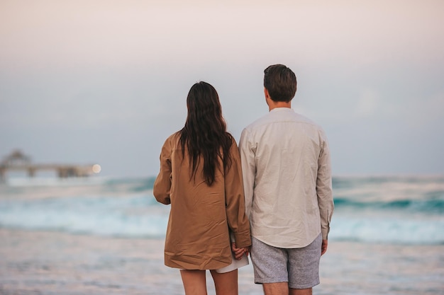 Jeune couple sur les vacances à la plage marchant au coucher du soleil