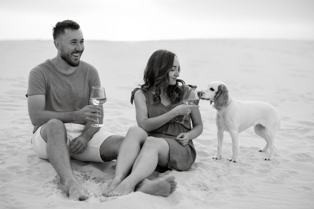 Jeune couple en vêtements orange avec chien dans le sable blanc du désert