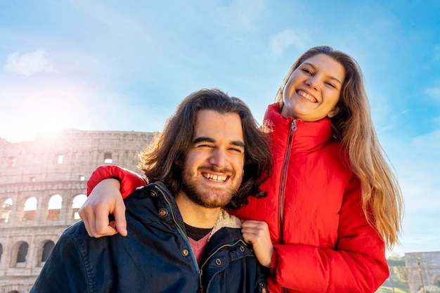 Jeune couple voyageant à Rome le couple sourit et prend un selfie devant le Colisée