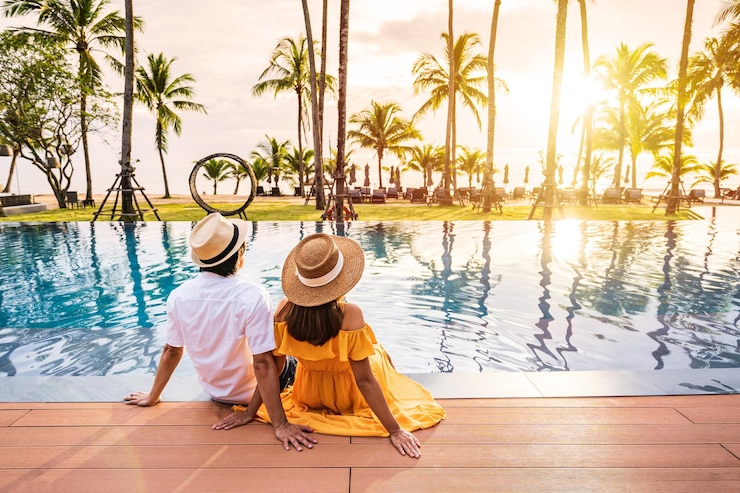 Photo un jeune couple de voyageurs se détend et profite du coucher de soleil près d'une piscine de villégiature tropicale lors d'un voyage de vacances d'été