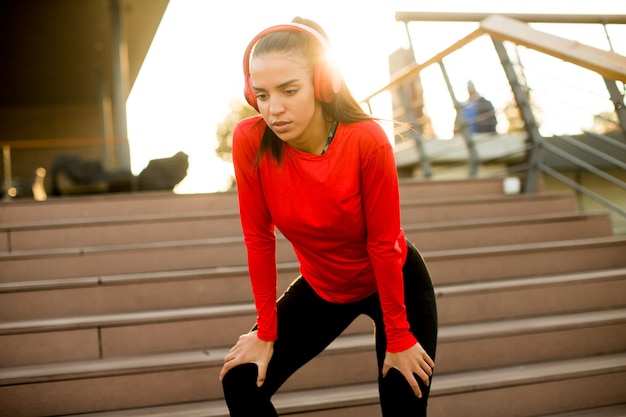 Jeune coureur féminin attrayant prenant une pause après le jogging en plein air