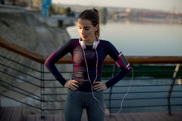 Jeune coureur féminin attrayant prenant une pause après le jogging en plein air