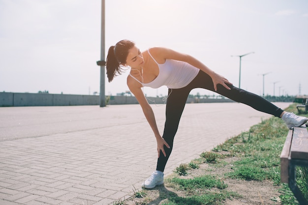 Photo jeune coureur de fitness femme étirant les jambes avant de courir