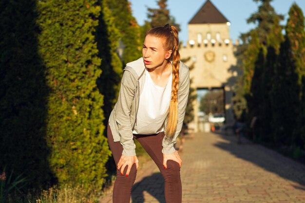 Jeune coureuse, athlète fait du jogging dans la rue de la ville au soleil.