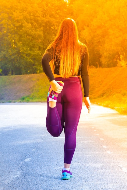 Une jeune coureuse de fitness étirant les jambes avant de courir sur le stade Une femme s'étire avant de courir