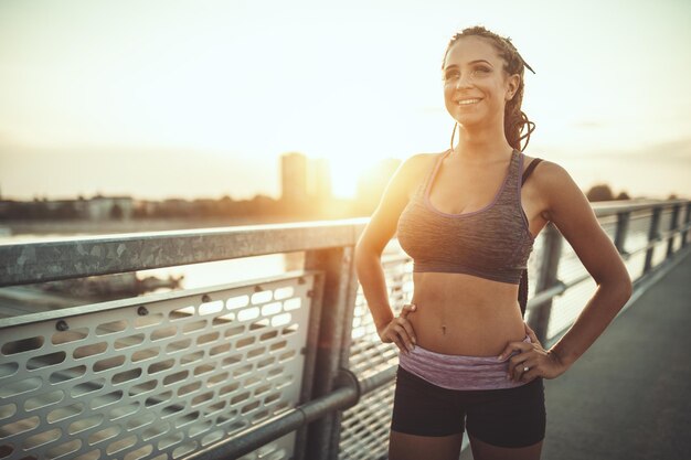 Une jeune coureuse se prépare à courir et à faire de l'exercice le matin sur un pont de rivière.