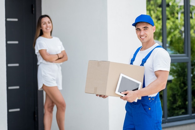 Jeune coursier livrant des marchandises à une jeune femme à la maison