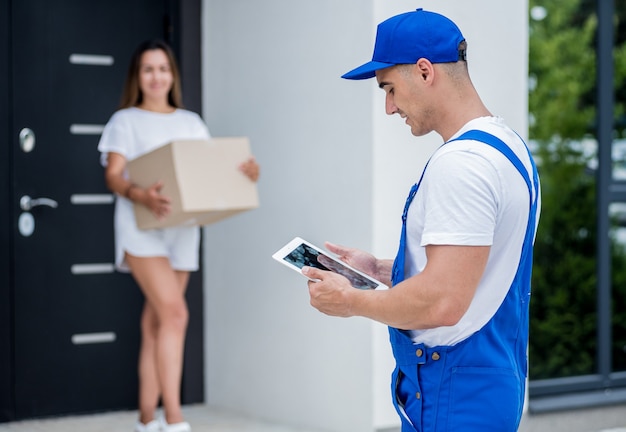 Jeune coursier livrant des marchandises à une jeune femme à la maison