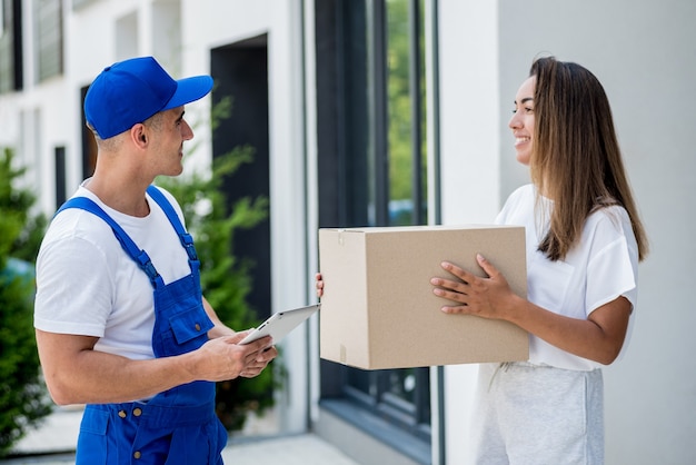 Jeune coursier livrant des marchandises à une jeune femme à la maison