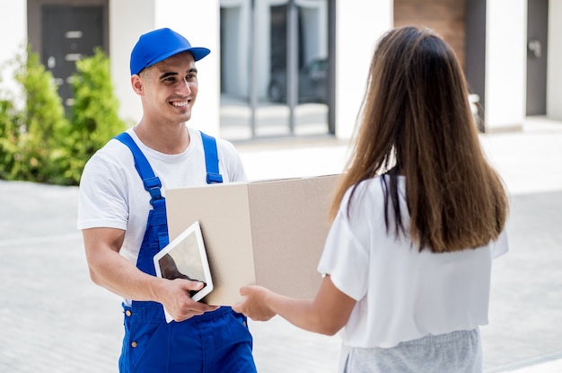 Jeune coursier livrant des marchandises à une jeune femme à la maison