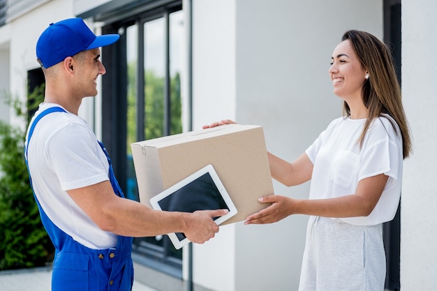 Jeune coursier livrant des marchandises à une jeune femme à la maison