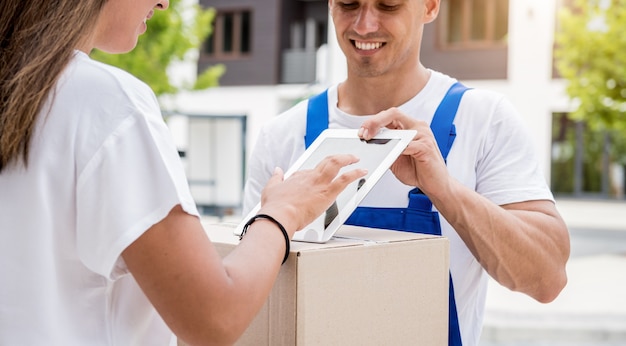 Jeune coursier livrant des marchandises à une jeune femme à la maison