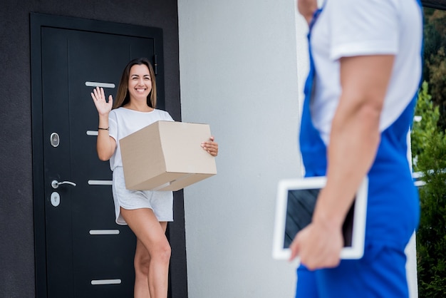 Jeune Coursier Livrant Des Marchandises à Une Jeune Femme à La Maison.