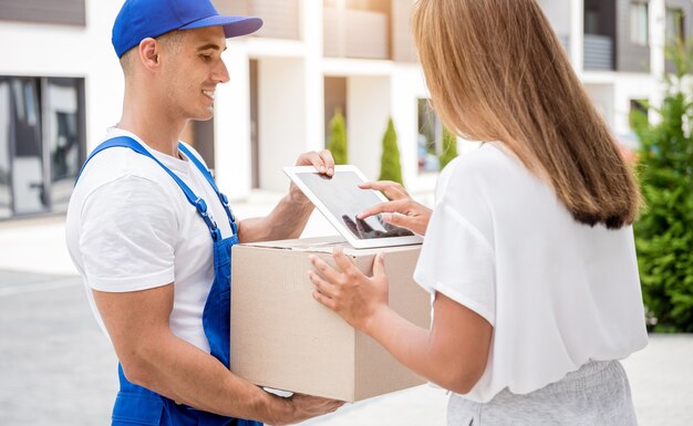 Jeune coursier livrant des marchandises à une jeune femme à la maison.