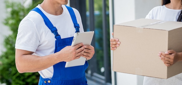 Jeune coursier livrant des marchandises à une jeune femme à la maison