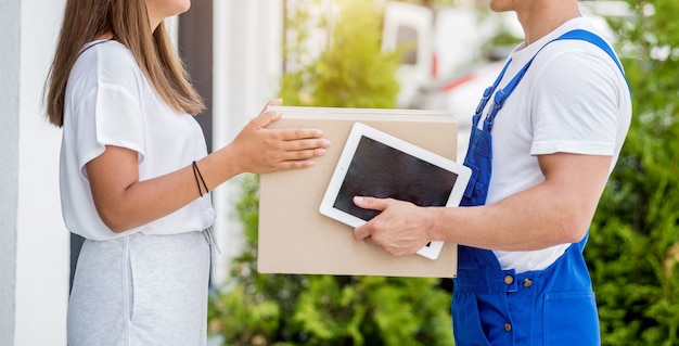 Jeune coursier livrant des marchandises à une jeune femme à la maison