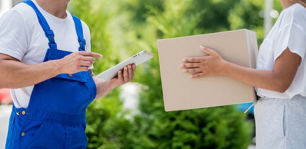 Jeune coursier livrant des marchandises à une jeune femme à la maison