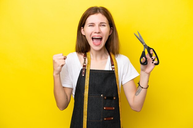 Jeune couturière anglaise femme isolée sur fond jaune célébrant une victoire en position de gagnant