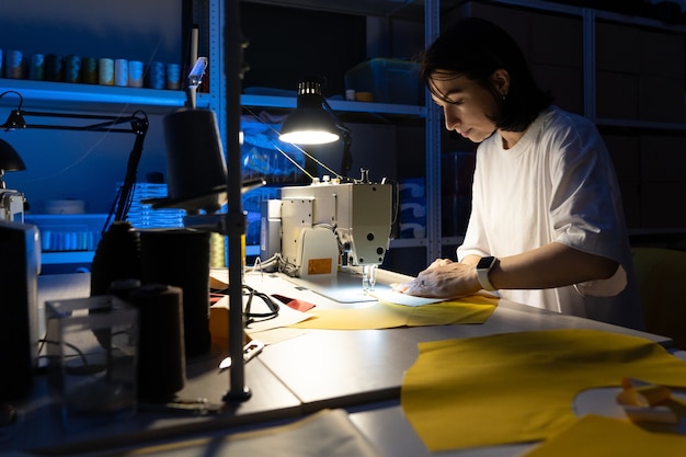 Jeune couturière sur le lieu de travail coudre sur machine à coudre couturière travail en atelier studio ou atelier