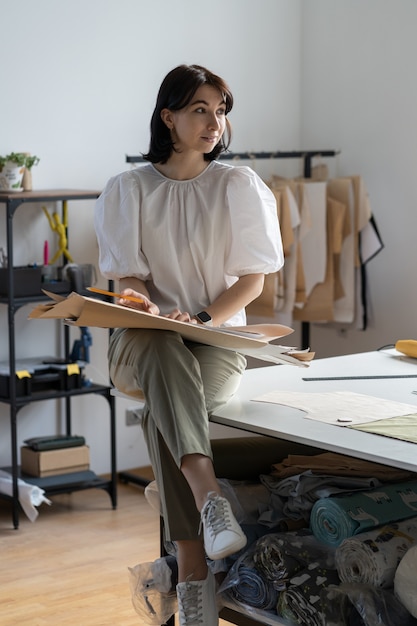 Jeune créateur de mode égout penser à de nouvelles idées de vêtements fille réfléchie tailleur dans l'atelier atelier