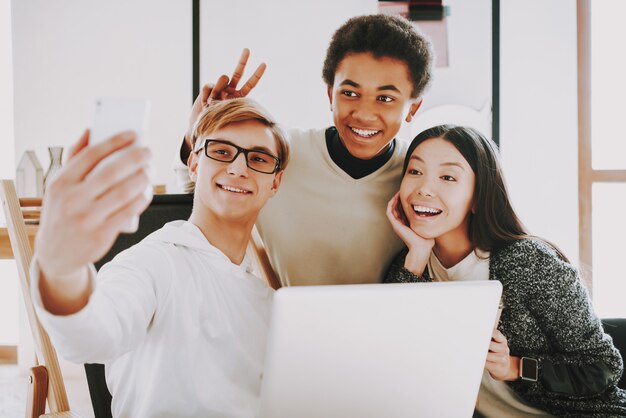 Jeune créateur souriant faisant selfie avec des collègues